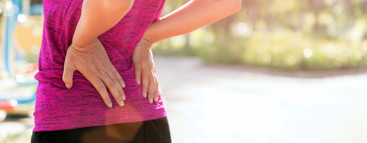 Young asian woman feel pain on her back and hip while exercising, health care concept.